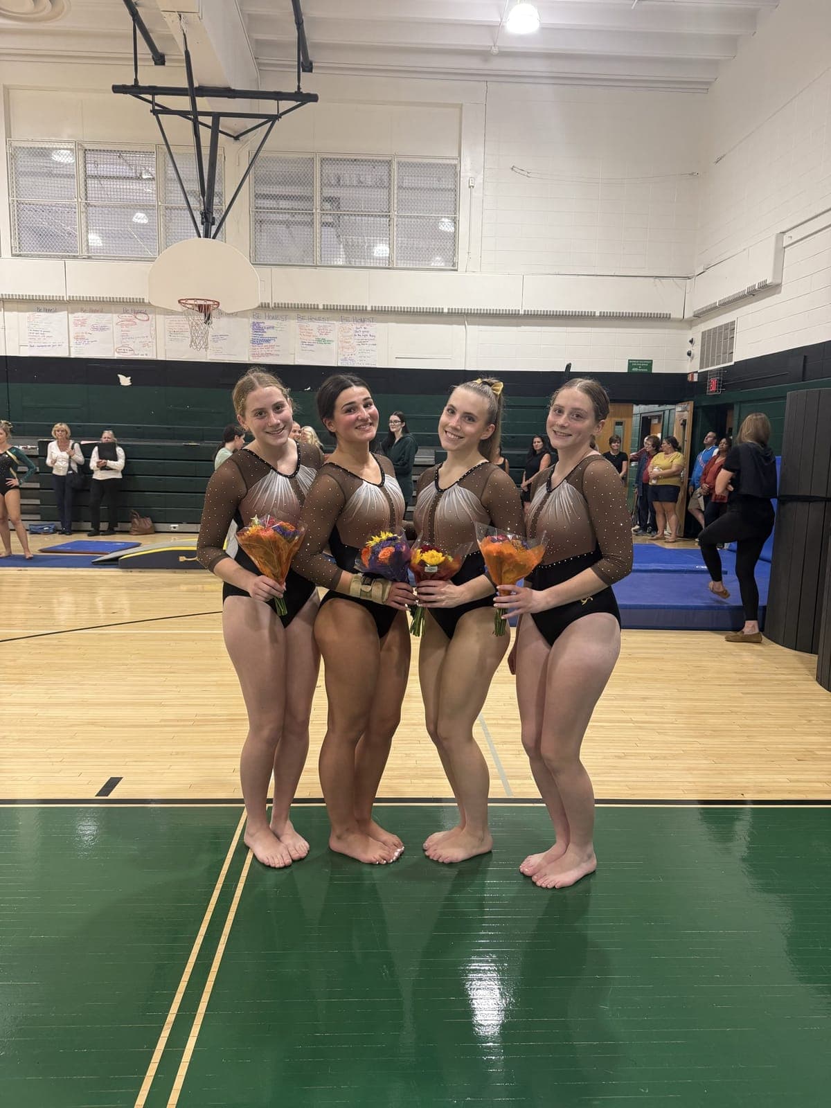 Watchung Hills gymnastics seniors with flowers after being recognized.